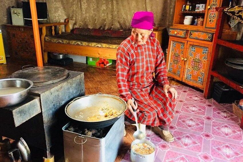 Una persona cocinando en una cocina tradicional con una estufa grande, ollas y un armario colorido. 2