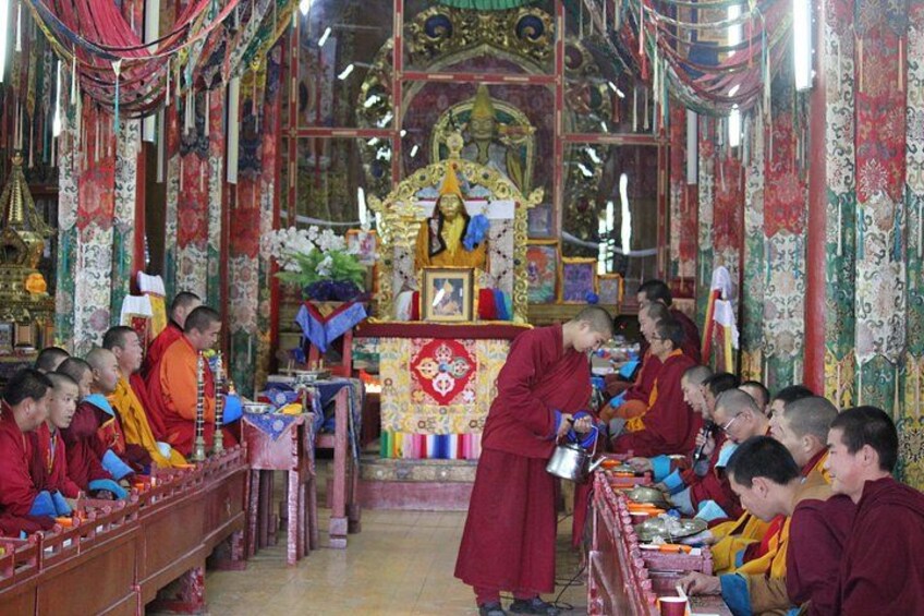 Eine Gruppe von Mönchen in einem prunkvoll ausgestatteten Tempel, die an einer religiösen Zeremonie teilnehmen. 2