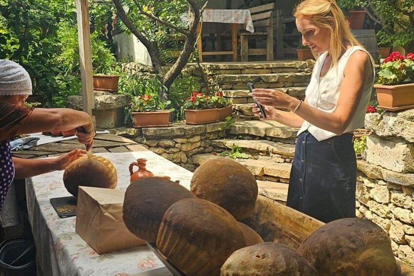 A person preparing food outdoors with a table full of large, round objects and a woman using a smartphone. 5