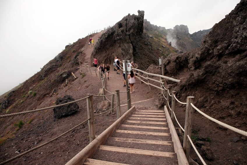 A rocky mountain trail with wooden steps and railings leading to a peak. 5