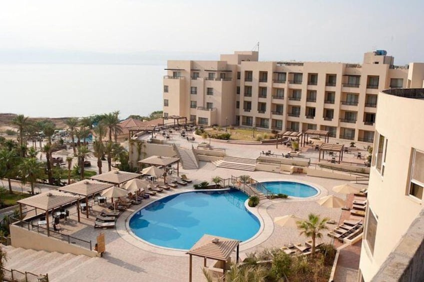 A resort with a large pool, palm trees, and a view of the sea. 5