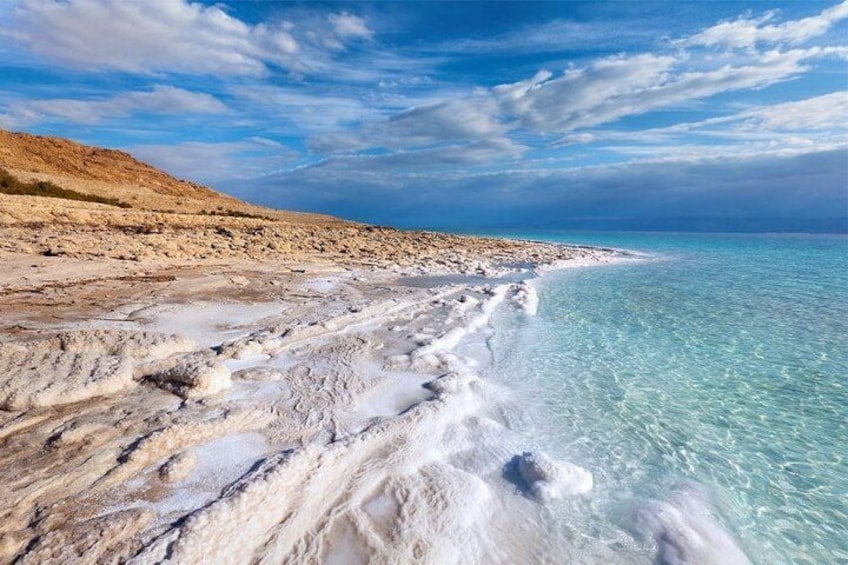 A coastal landscape with clear turquoise waters, white sandy beach, and a rocky cliff. 3