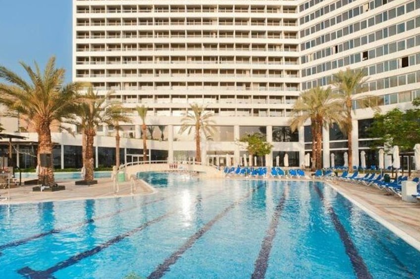 A swimming pool with blue water, surrounded by palm trees and lounge chairs. 2