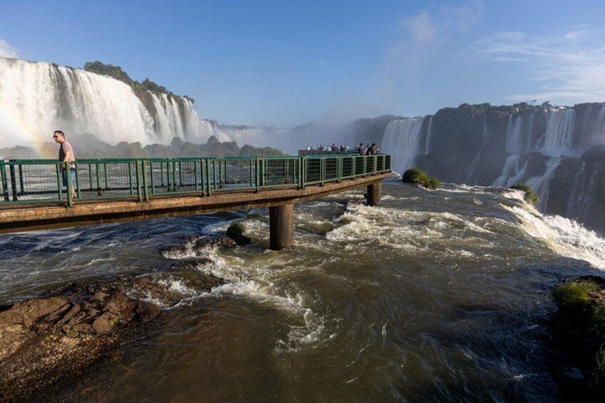 A bridge over a waterfall with people on it. 2