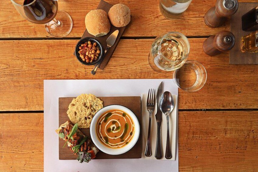 A meal with soup, bread, and a side salad on a wooden table. 5