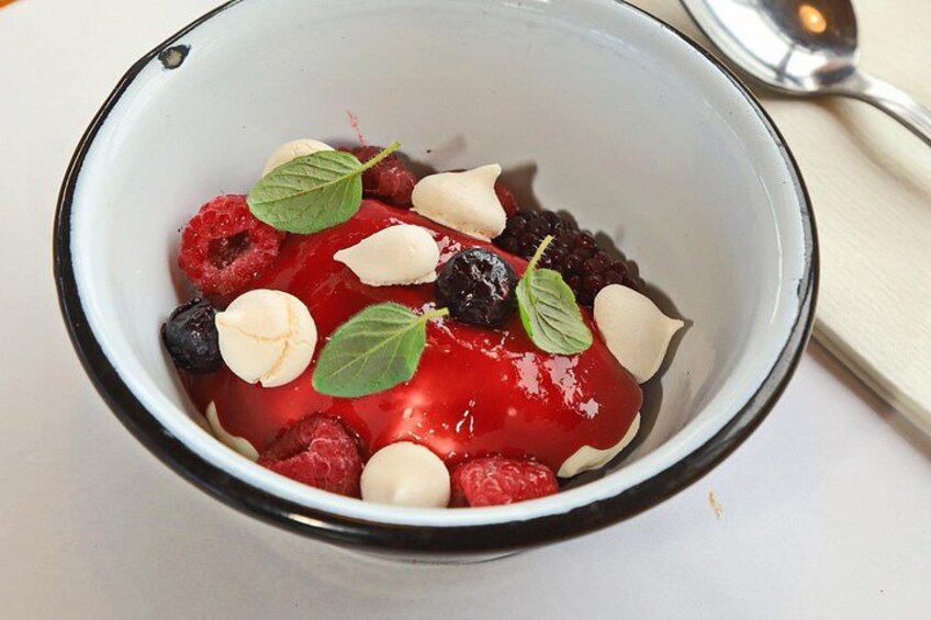 A bowl of dessert with berries, almonds, and mint leaves. 2