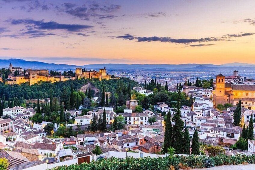 Una ciudad histórica con un castillo imponente en una colina, rodeada de edificios residenciales y vegetación. 4