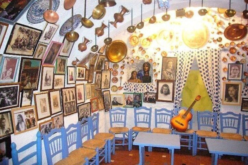 Una habitación con sillas azules, una guitarra y varias fotos enmarcadas en las paredes. 2