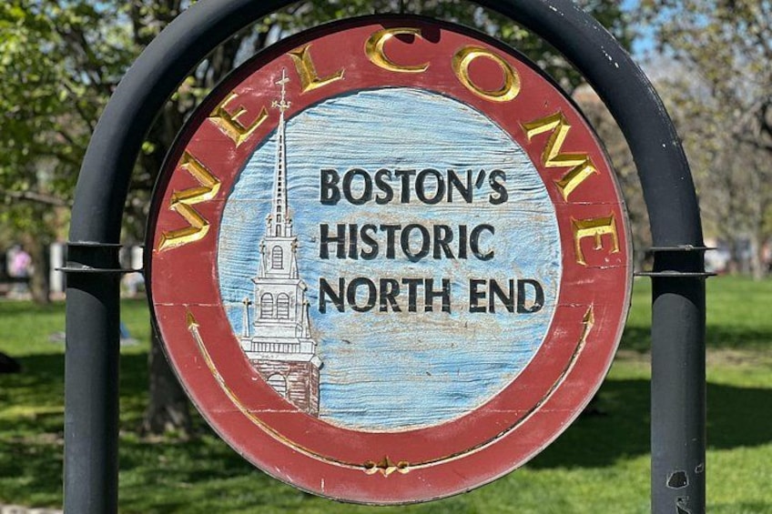 Segno circolare con un'illustrazione di una chiesa e testo che accoglie i visitatori nel quartiere storico North End di Boston. 5