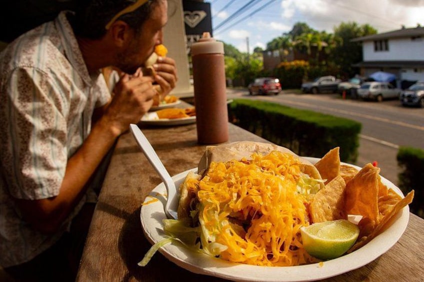 Une personne est assise à une table à l’extérieur et mange dans une assiette, avec un quartier de citron vert et une boisson à portée de main. 5