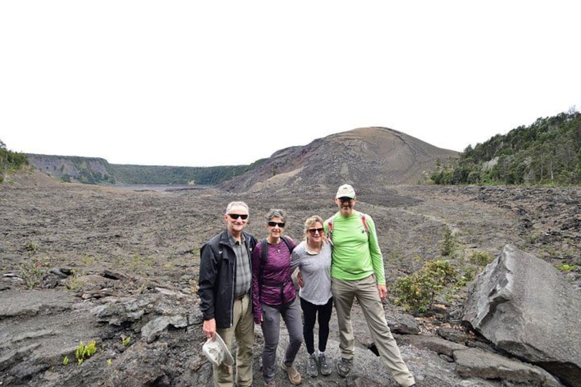 Un groupe de personnes se tient sur un terrain rocheux, avec un paysage volcanique en arrière-plan. 2