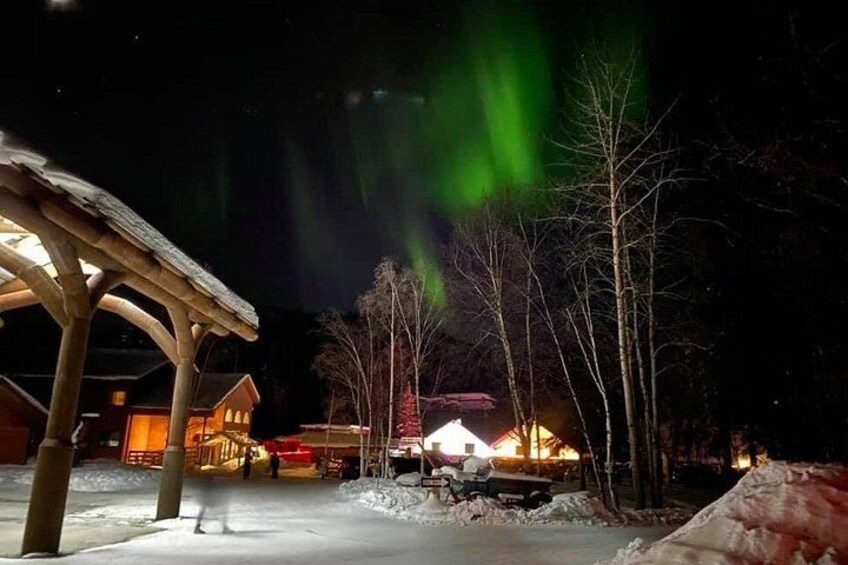 A snowy landscape with a wooden structure and a building with lights. 5