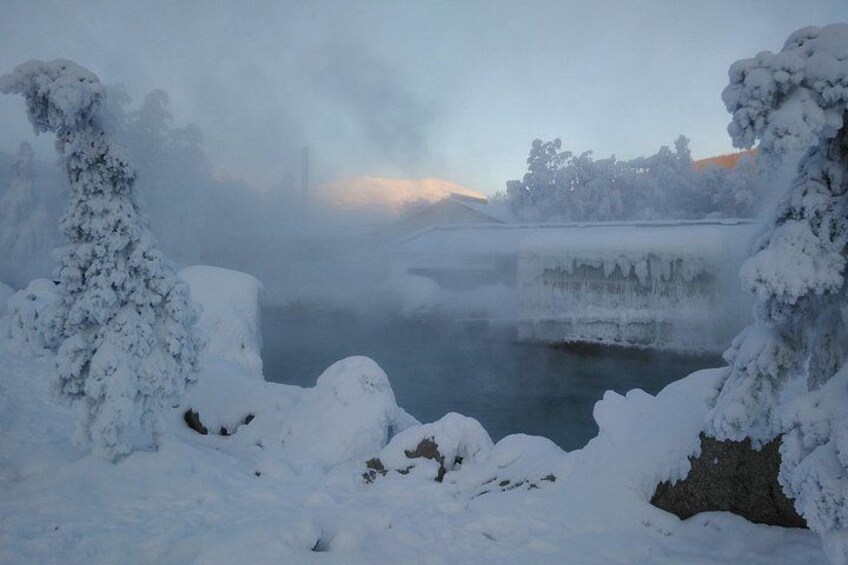 A snow-covered landscape with a frozen river, snow-laden trees, and a misty background. 3