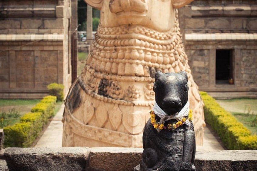 A stone sculpture of a bull with a dog statue in front. 2
