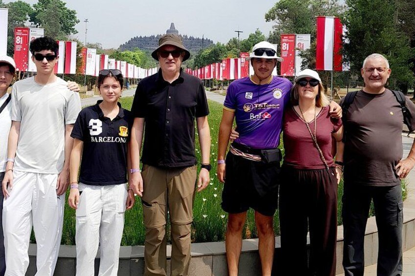A group of people standing in a line outdoors with flags in the background. 3