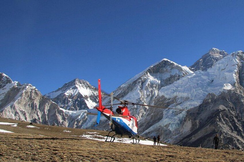 A helicopter on a landing pad with snow-capped mountains in the background. 1