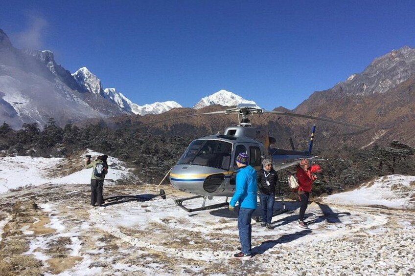 A helicopter on a snowy ground with mountains in the background. 5