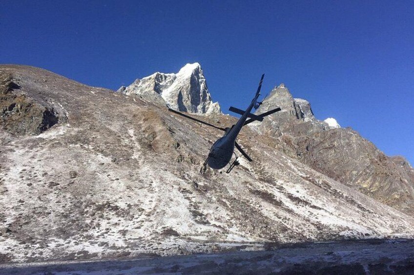 A helicopter on a snowy mountain with a clear sky. 4