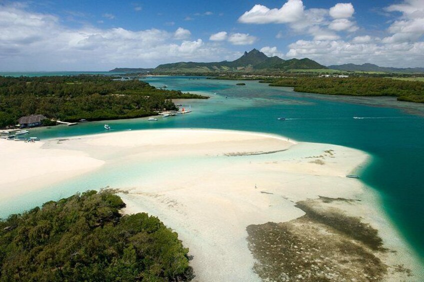 A coastal landscape with a sandy beach, turquoise waters, and a forested area. 2