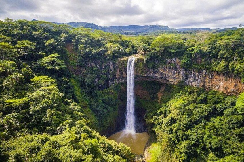 A waterfall surrounded by lush greenery and a mountainous landscape. 2