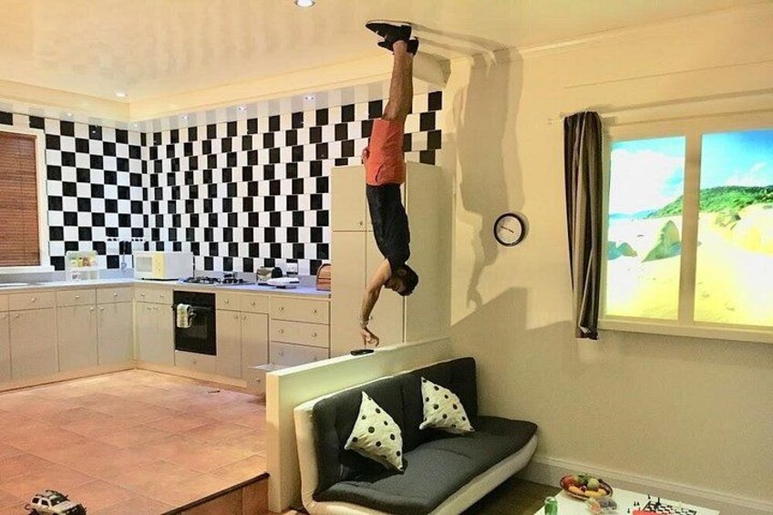 A person performing an acrobatic handstand on a kitchen counter. 5