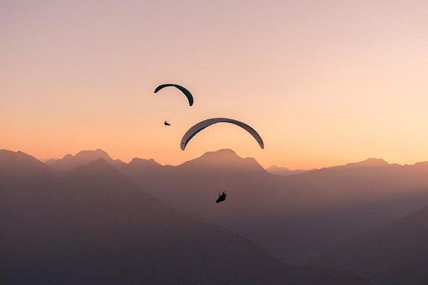 A person paragliding over a mountainous landscape during sunset. 4