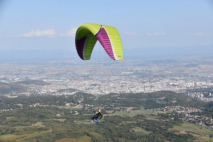 A person paragliding over a landscape with a city in the background. 3