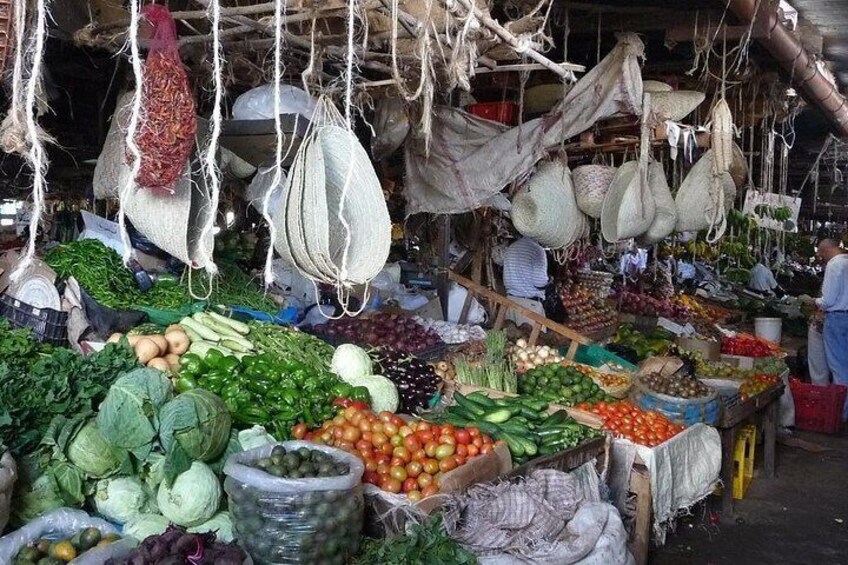 Een markt met diverse groenten en fruit, gepresenteerd in manden en opgehangen aan het plafond. 3