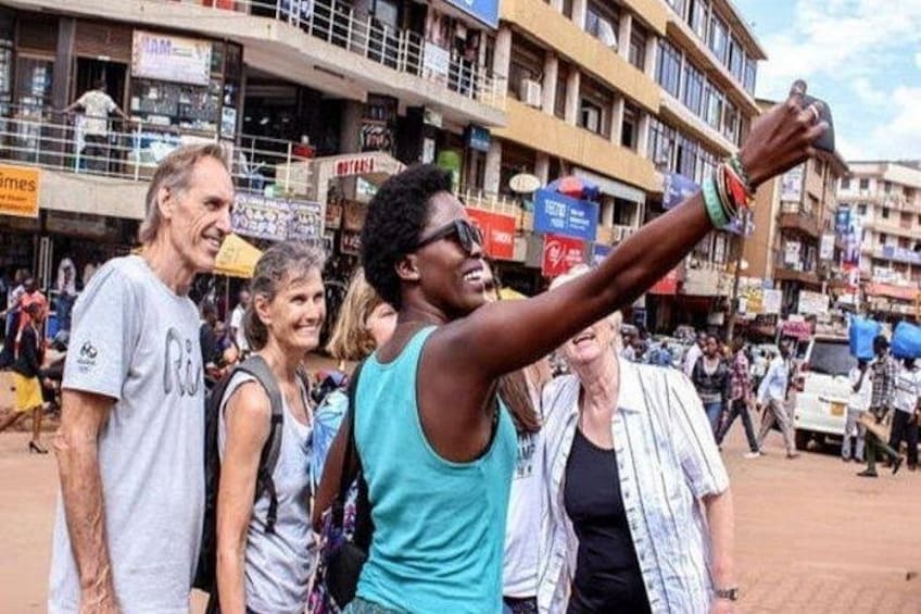 A busy street with people taking a selfie, buildings, and shops. 1
