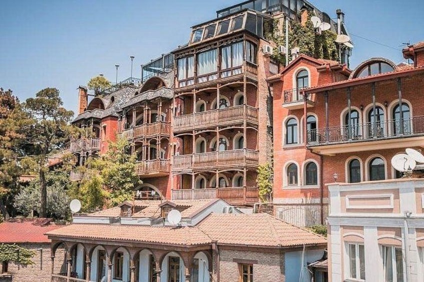 Een meerhoog gebouw met balkons, een rode baksteenvoorgevel en schotels. 1