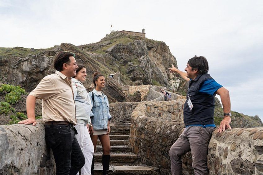 A group of people standing on a rocky staircase with a lighthouse in the background. 2