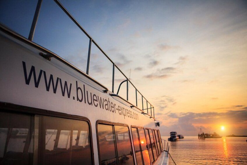 A boat with the website 'www.bluewater-express.com' on its side, set against a sunset over water. 1