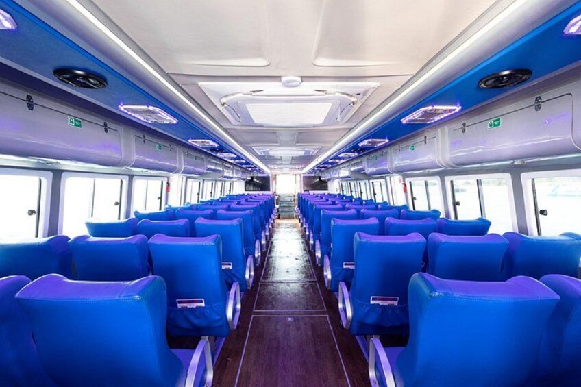 A train interior with rows of blue seats and overhead compartments. 3