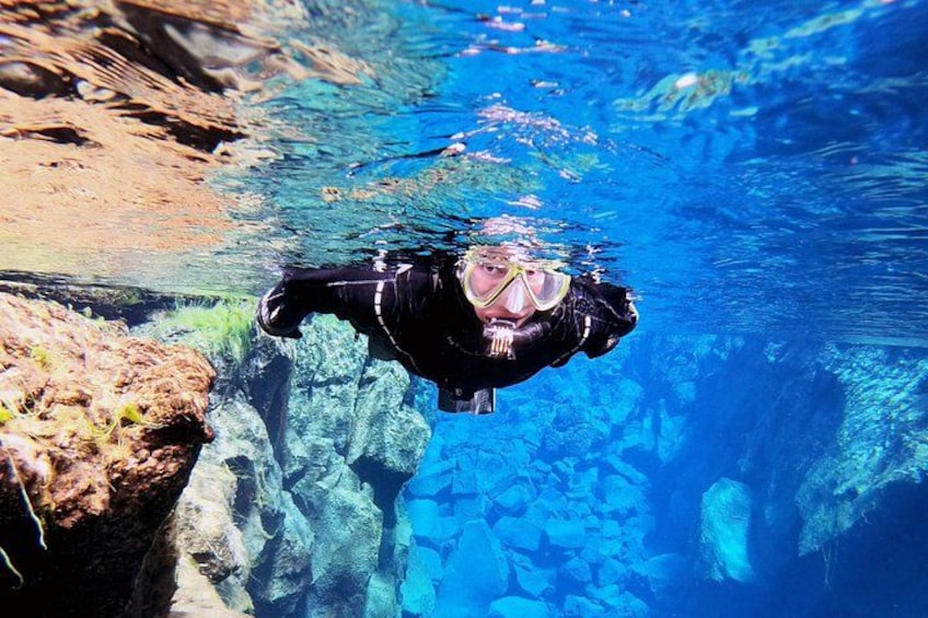 A person swimming underwater near rocky formations. 3