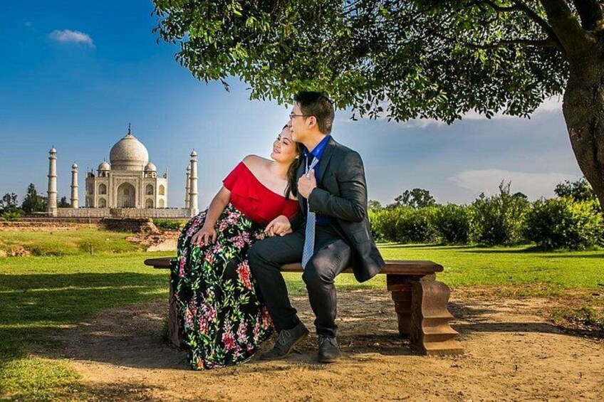 A couple sitting on a bench with the Taj Mahal in the background. 4