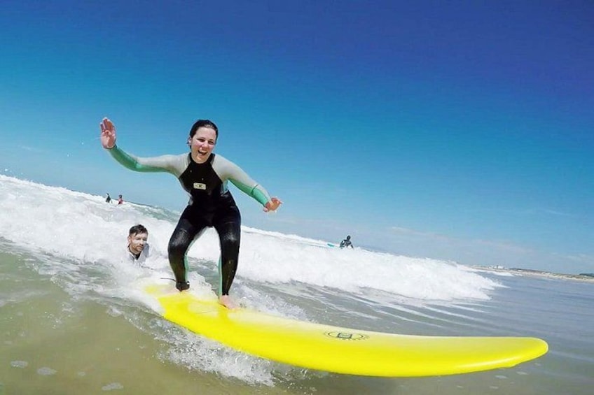 A person surfing on a yellow board, ocean waves, and other surfers in the background. 1