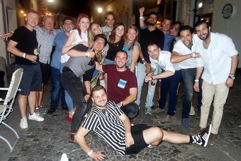 A group of people posing for a photo in an outdoor setting with cobblestone flooring. 2