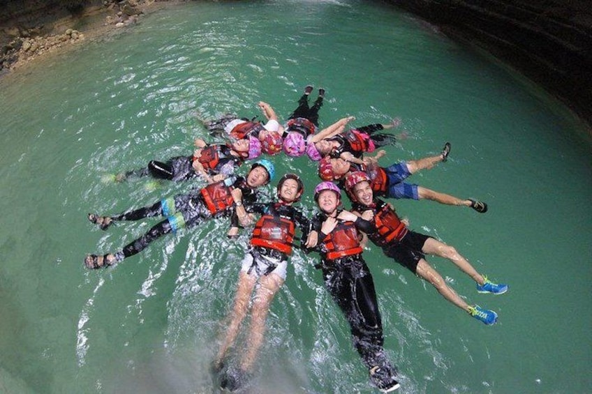 A group of people floating in a body of water, wearing life jackets. 5