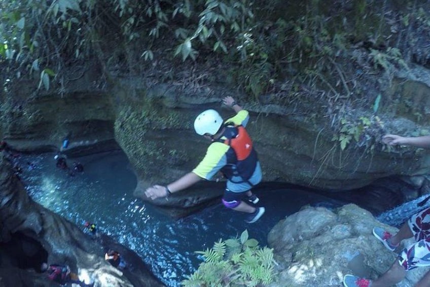 A person rappelling down a rocky cliff into a water body surrounded by vegetation. 3