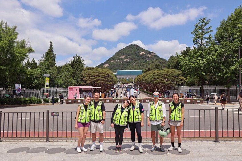 A group of people in safety vests standing in a line on a sunny day. 5
