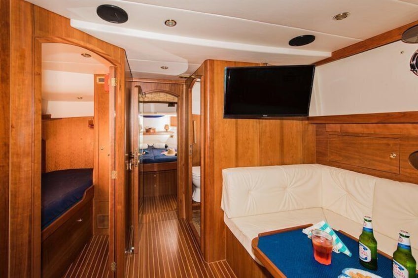 A compact interior with a bunk bed, a small kitchenette, a TV, and a dining area with bottles. 2