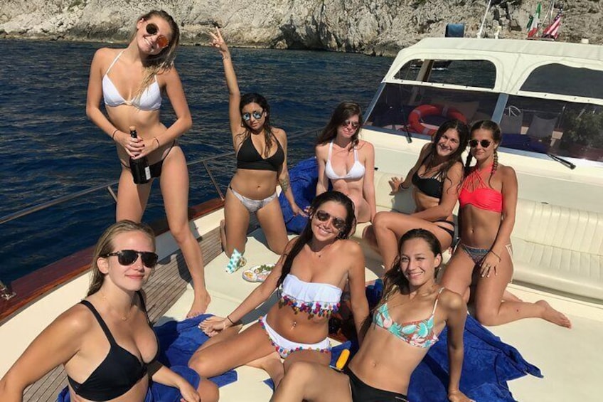 A group of people on a boat in a body of water with rocky cliffs in the background. 4