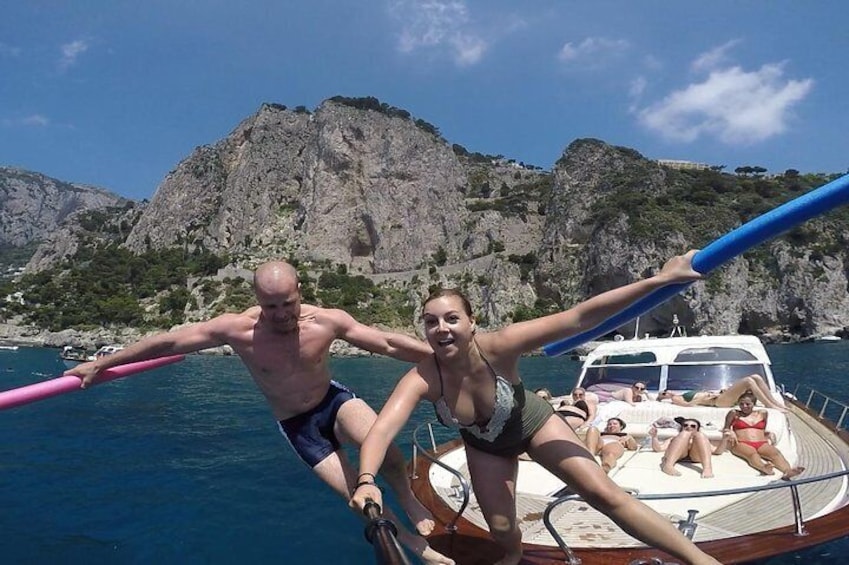A man and a woman on a boat with rocky cliffs in the background. 1