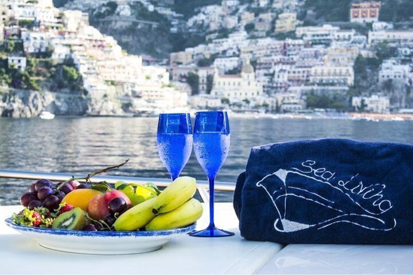 A table with a fruit platter, two blue glasses, and a towel with a design. 5