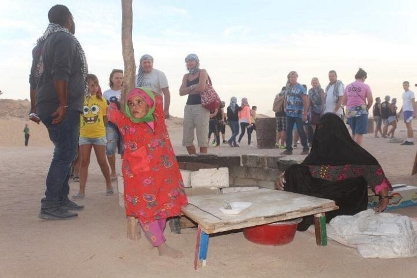 Una playa arenosa con gente, una mesa de madera y un cubo rojo. 2