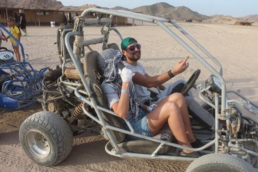 En person i en terränggående buggy med ratt och stora däck. 1