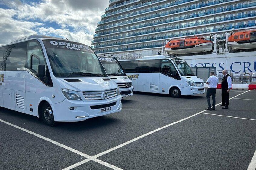 A cruise ship docked with two white buses parked in front. 5
