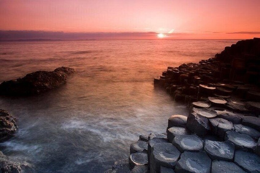 A sunset over a rocky coastline with calm water. 4