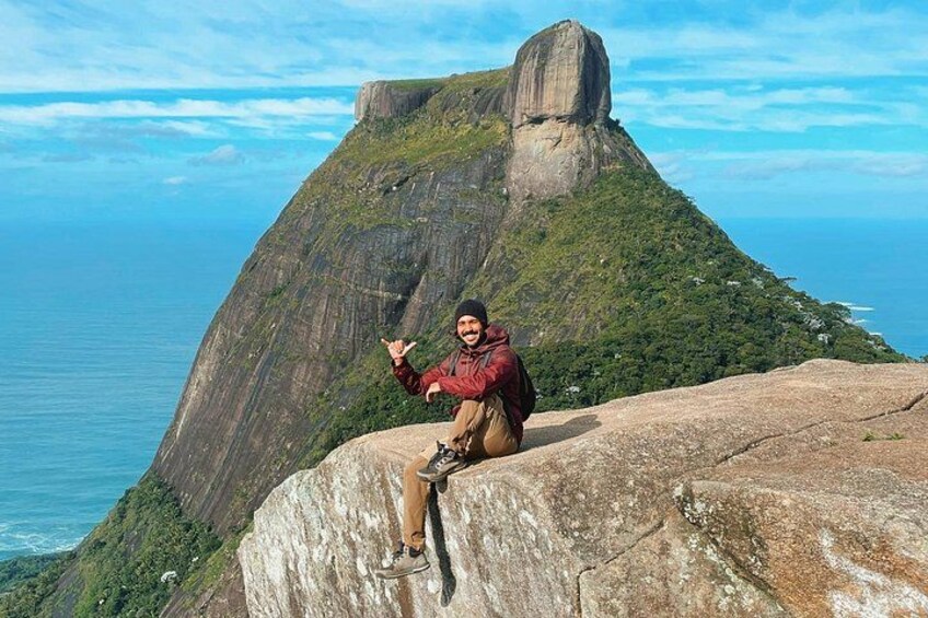 A person sitting on a rock with a mountain in the background. 1