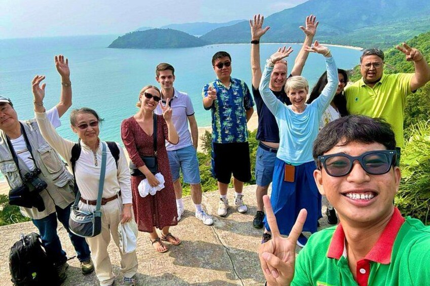 Un grupo de personas en un saliente de piedra con vista a una masa de agua y montañas al fondo. 2